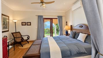 Een slaapkamer met een bed, bureau, stoel, plafondventilator en uitzicht op het omliggende landschap.