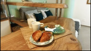 Een houten tafel met een bord croissants, een kopje en een glazen pot.