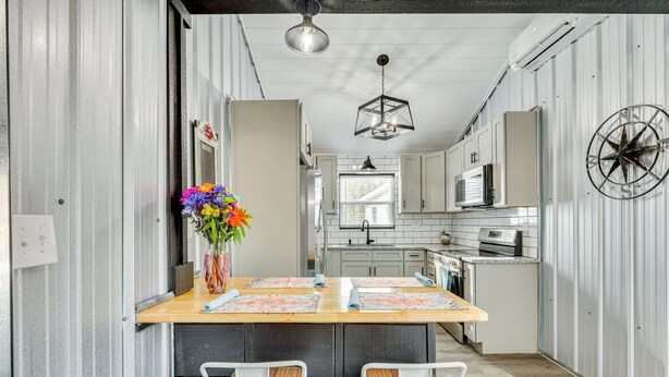 Una cocina moderna con una isla central, armarios blancos y un adorno decorativo con forma de brújula.