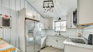Una cocina moderna con armarios blancos, electrodomésticos de acero inoxidable y salpicadero de azulejos.