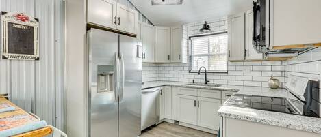 A modern kitchen with white cabinets, stainless steel appliances, and a tiled backsplash.