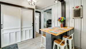 Un área de cocina con una mesa de madera, taburetes de bar y un jarrón con flores.
