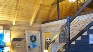 Un salon chaleureux avec un canapé bleu, une table basse en bois et un escalier doté d’une rampe en métal.