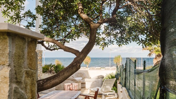 Une terrasse avec des meubles d’extérieur, une table et une vue sur la mer.