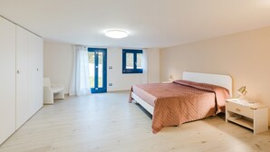Une chambre à coucher comprenant un lit, une table de chevet et une porte donnant sur une autre pièce.