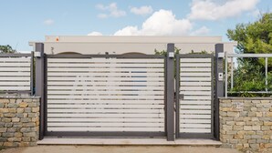 Une entrée fermée par un portail, avec un mur en pierre et un portail en métal.