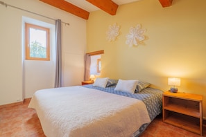 A bedroom with a bed, a nightstand, a lamp, a window, and decorative wall art.
