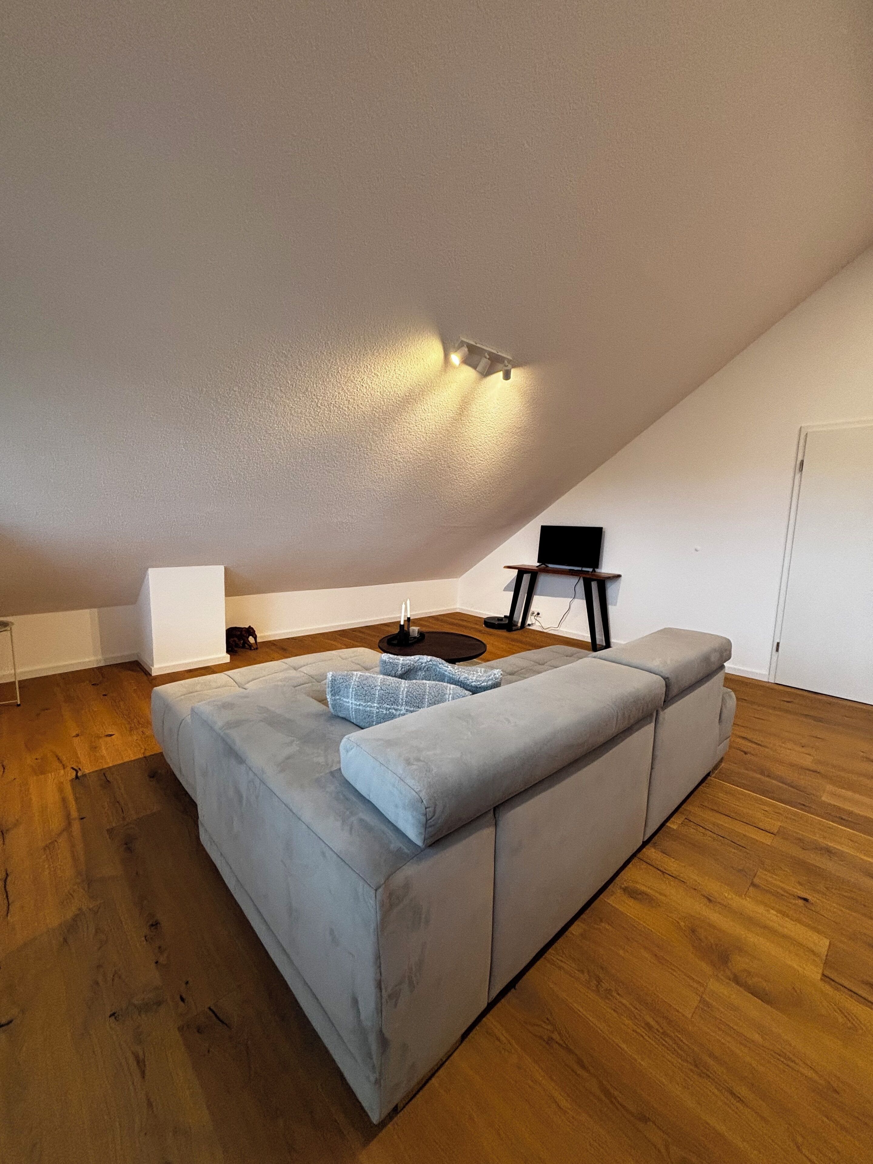 Ein stilvolles Loft-Zimmer mit einer großen Eckcouch, einem kleinen Tisch und einem Flachbildfernseher.