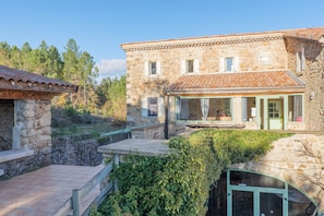 Un bâtiment en pierre avec un toit en tuiles, un porche couvert et un escalier en pierre.