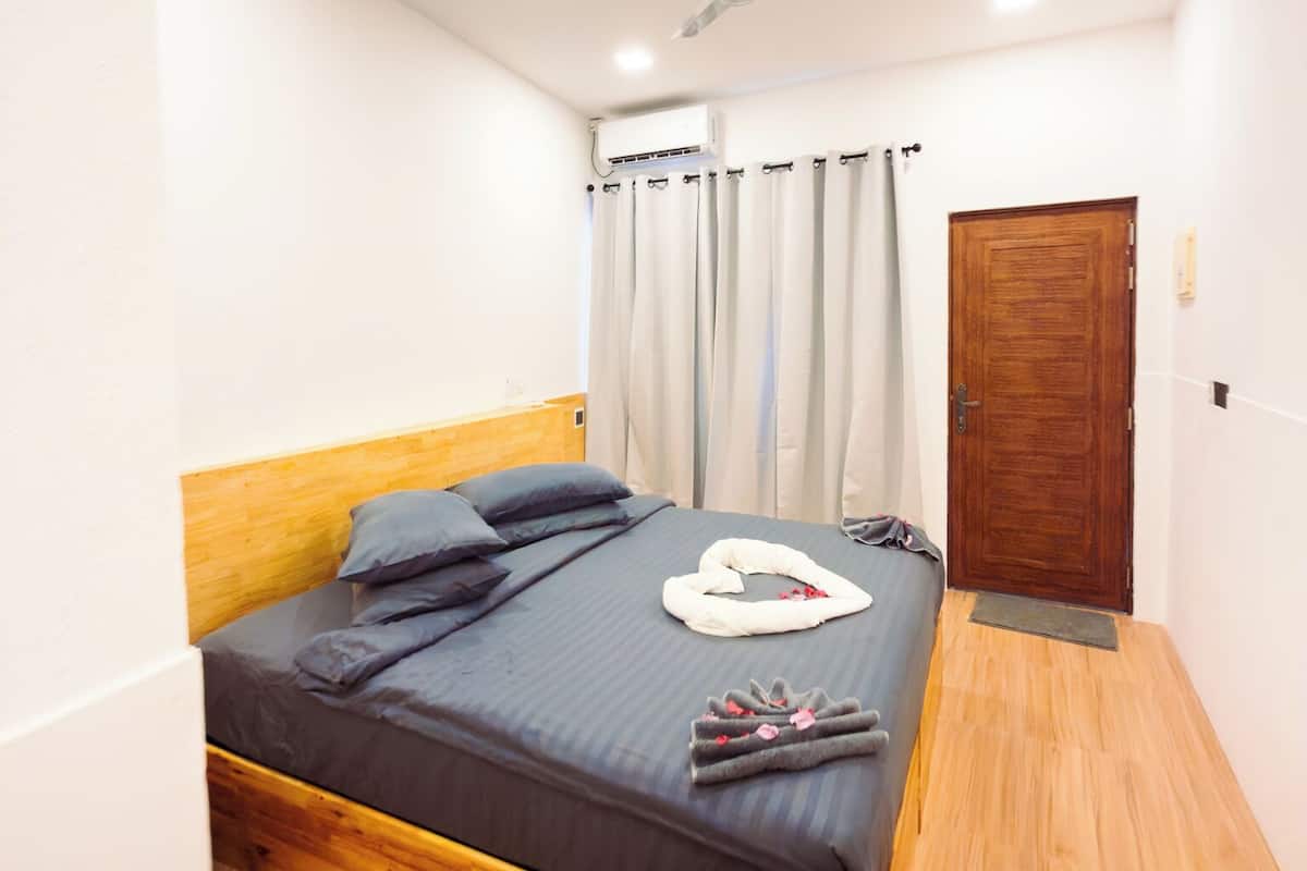 A bedroom with a wooden bed, a ceiling fan, and a door.