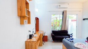 Una habitación moderna con un escritorio de madera, una cama, un ventilador de techo y vistas a zonas verdes.