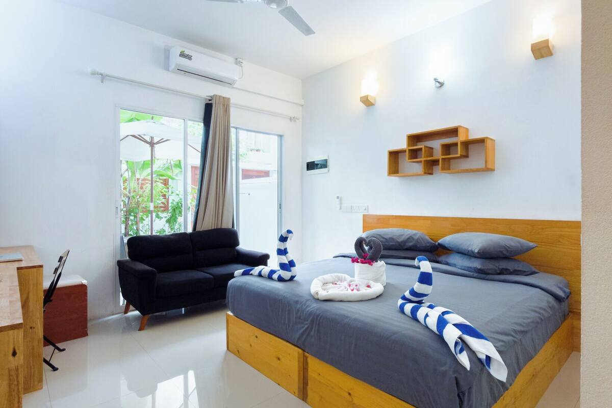 A modern bedroom with a wooden bed, a ceiling fan, a desk, and a window with curtains.