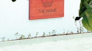 Una pared roja con un logotipo y el texto que dice "THE WAVE DHIGURAH".