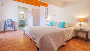 A bedroom with a bed, a desk, a chair, and a nightstand with a lamp. - "Turquoise" Guest Room at Perles de aime – Ardèche Farmhouse Retreat (Laurac-en-Vivarais)