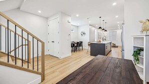 A modern interior with a wooden staircase, a dining area, and a kitchen. - Indoor Fireplace • 3 Kings • Free Parking • Desk (Calgary)