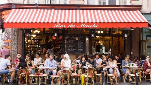 Un caffè all'aperto con tenda a righe rosse e sedie in vimini.