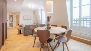 Un'area pranzo moderna con un tavolo rotondo e sedie, un lampadario e ampie finestre che offrono una vista.