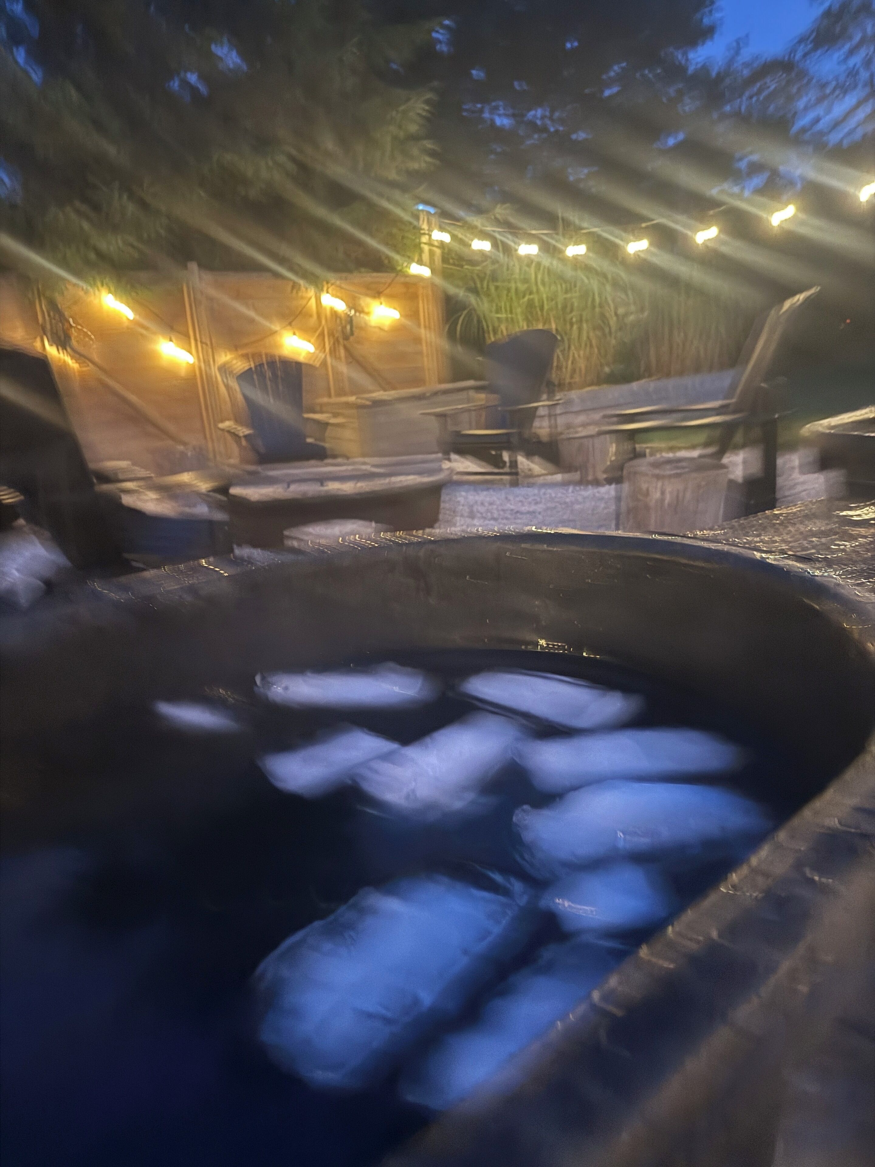 Ein Whirlpool mit Eiswürfeln, umgeben von Gartenmöbeln und Lichterketten.