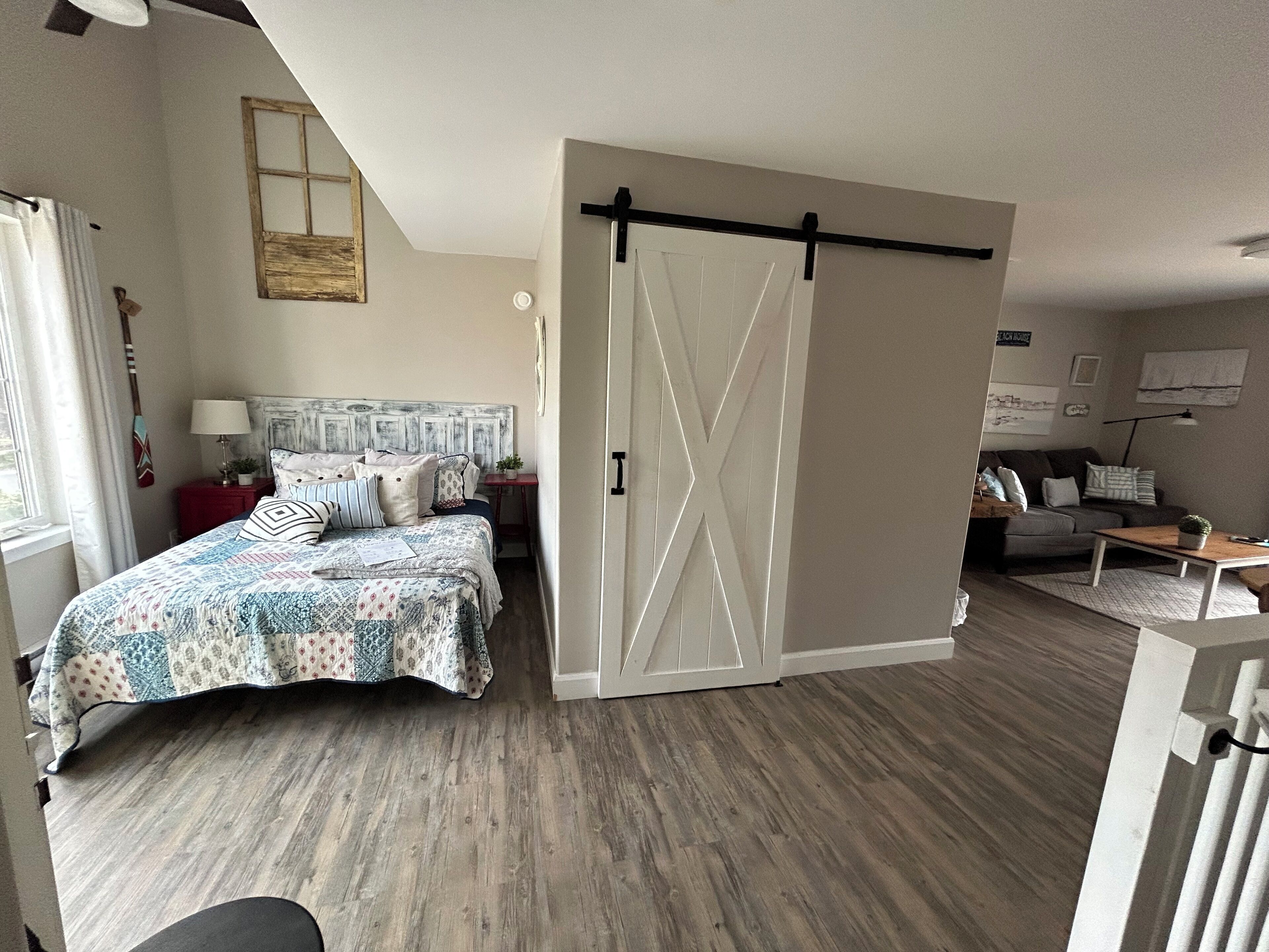 Um quarto com cama, mesa de cabeceira, cômoda, porta de correr, sofá e mesa de centro.