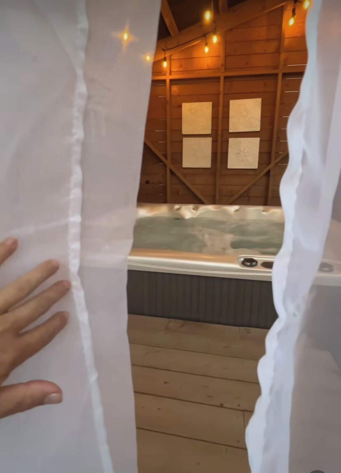 Interior de una cabaña de madera con jacuzzi e iluminación de guirnaldas.