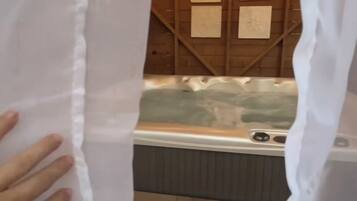 Interior de una cabaña de madera con jacuzzi e iluminación de guirnaldas.