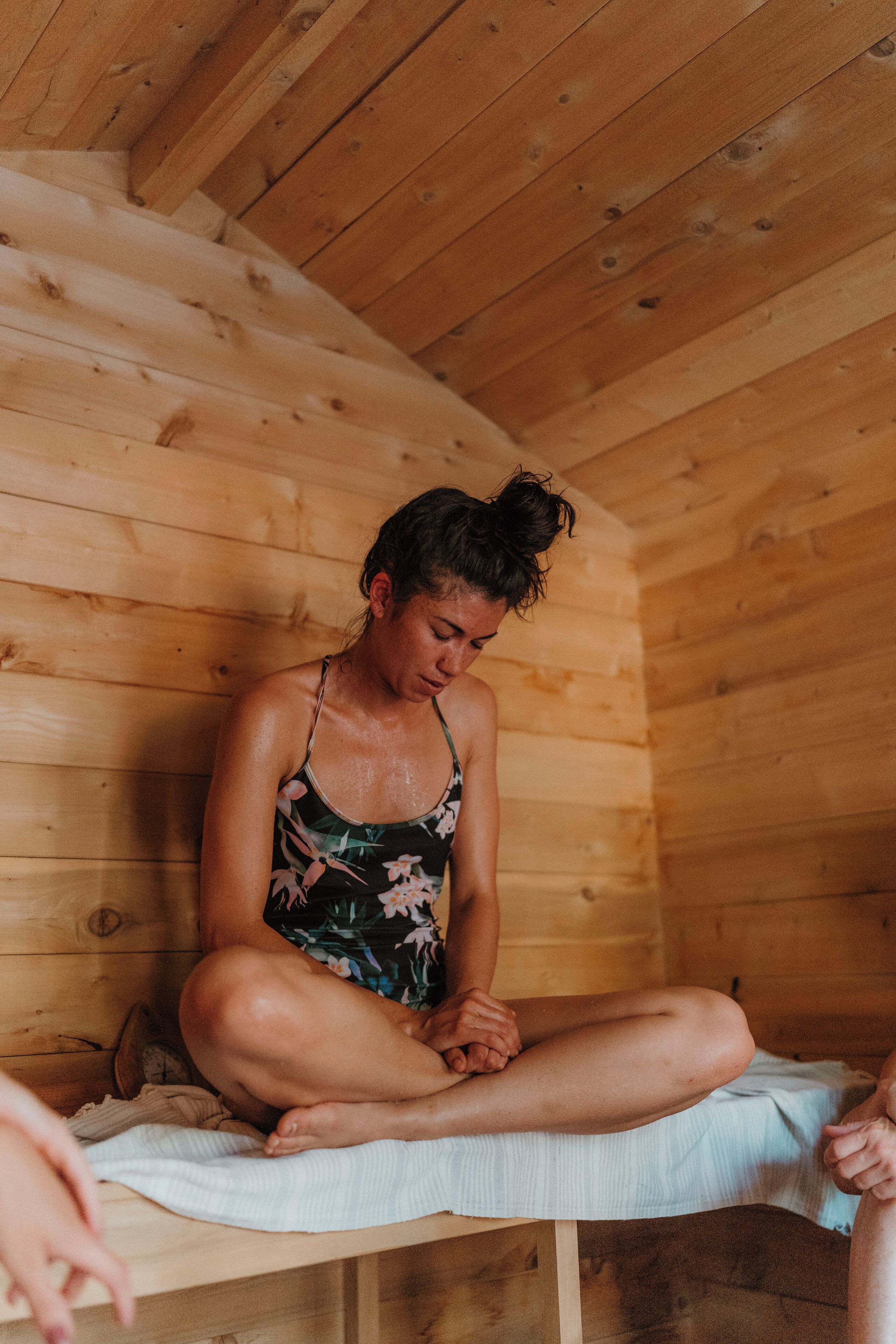 A wooden cabin interior with a person sitting on a bench.