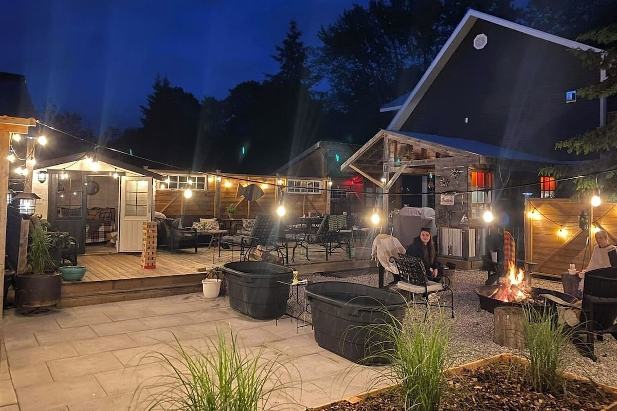 An outdoor patio area with seating, a fire pit, and string lights.