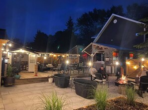 An outdoor patio area with seating, a fire pit, and string lights. - The Klinck House (Nottawa)