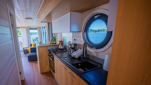 Una cocina compacta con ventana, armarios de madera y vista al agua.