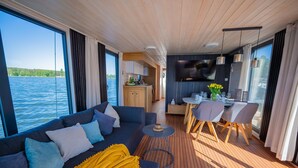 Un interior moderno con sofá, mesa de comedor y zona de cocina, con vista a una masa de agua.