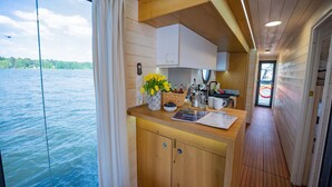 Une cuisine avec des meubles en bois, un comptoir agrémenté d’un vase de fleurs et une vue sur l’eau à l’extérieur.