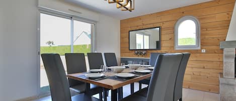 Un espace repas agrémenté d’un mur en bois, d’un grand miroir et offrant une vue sur l’extérieur.