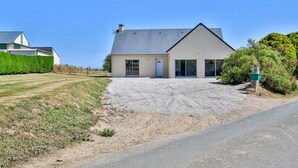 A two-story house with a gravel driveway leading to a front door. - Holiday Home "Gîte with Game Room" with Private Terrace, Garden & Wi-Fi (Montfarville)