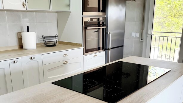Een moderne keuken met een centraal eiland, een inbouwoven en roestvrijstalen apparatuur.
