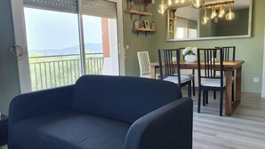 Een kamer met balkon, een eettafel met stoelen, een bank en een hanglamp.