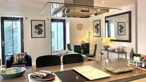 Una cocina moderna con estufa integrada, un comedor con mesa y sillas, y obras de arte en las paredes.