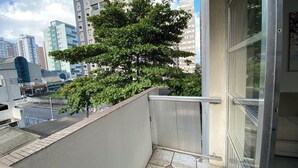 Un balcón con vistas a un paisaje urbano, que incluye edificios altos y un árbol.