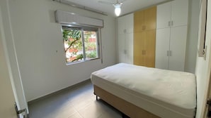 Un dormitorio con cama, ventana y armario.