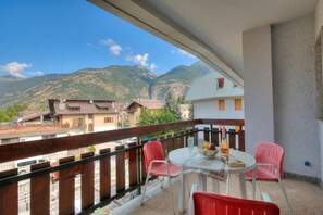Un balcon avec une table, des chaises et une vue sur les montagnes.