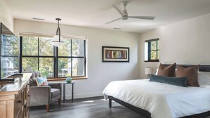 A bedroom with a bed, a chair, a desk, a ceiling fan, and large windows. - Stay at Old Garden Beach (Rockport)