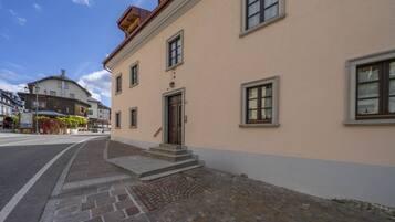 Ein Gebäude mit beiger Fassade, Stufen, die zu einer Tür führen, und ein gepflasterter Bürgersteig.