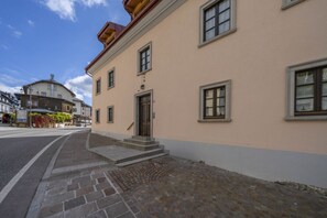 Ein Gebäude mit beiger Fassade, Stufen, die zu einer Tür führen, und ein gepflasterter Bürgersteig.