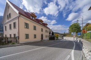 Un bâtiment à deux étages, avec un toit rouge, un mur en pierre et un ciel dégagé.