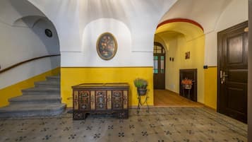 Eine Treppe mit Holzhandlauf, eine Sitzbank mit Blumenmuster, ein Wandbild und ein Blumentopf.