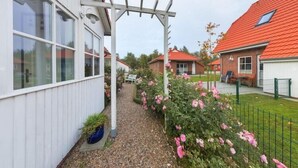 Il s’agit d’une propriété résidentielle à l’extérieur blanc, dotée d’un chemin de gravier et d’un jardin agrémenté de fleurs roses.