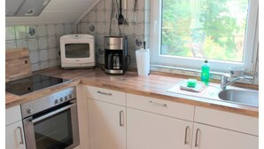 Una cocina con estufa, horno, tostadora, cafetera y ventana con vista a zonas verdes.