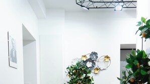 A hallway with a potted plant, white walls, and a tiled floor. - Notes in Corvetto by Wonderful Italy (Genoa)