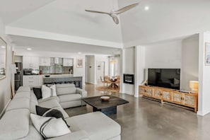 A spacious living area with a sofa, a television, and a dining table. - Sundrift—Sophisticated Beachside Retreat with Pool (Quindalup)
