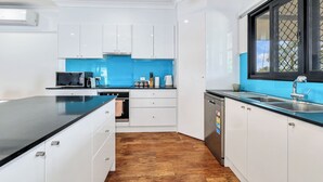 Eine moderne Küche mit weißen Schränken, einer schwarzen Arbeitsplatte und einer blauen Spritzschutzwand.