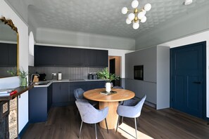 A modern kitchen with dark cabinetry, a round wooden table, and two chairs. - Luxury 2.5 Bedroom Flat in Southsea (Portsmouth)